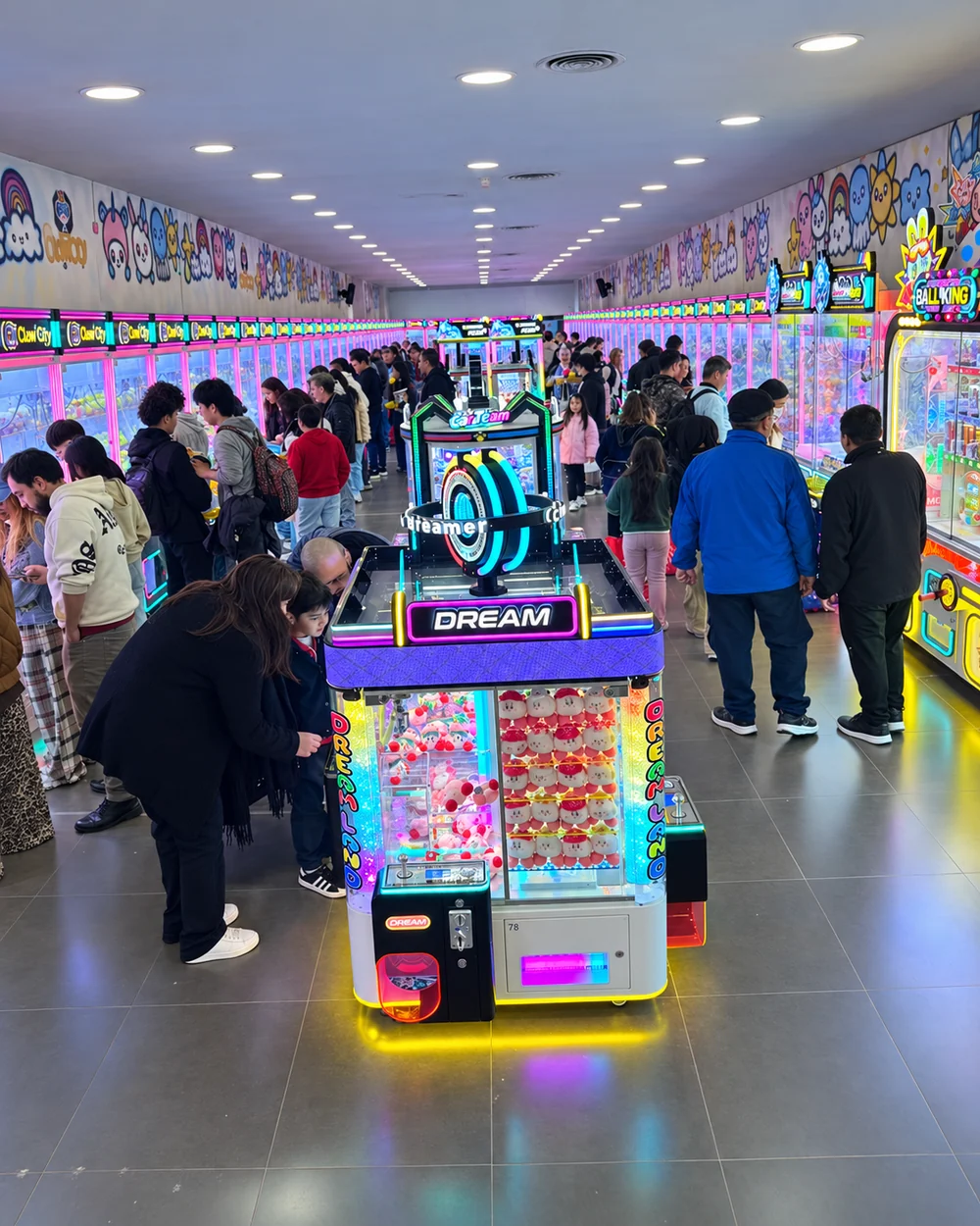 Busy commercial claw machine venue showing customer traffic and equipment layout